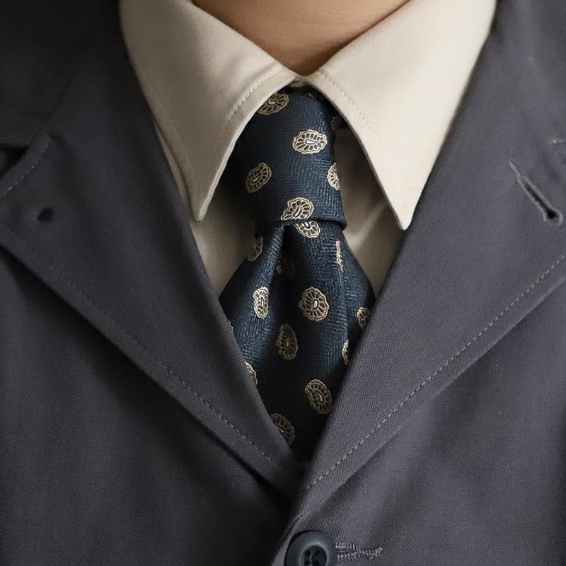 Dark navy patterned tie styled with a cream shirt and charcoal suit