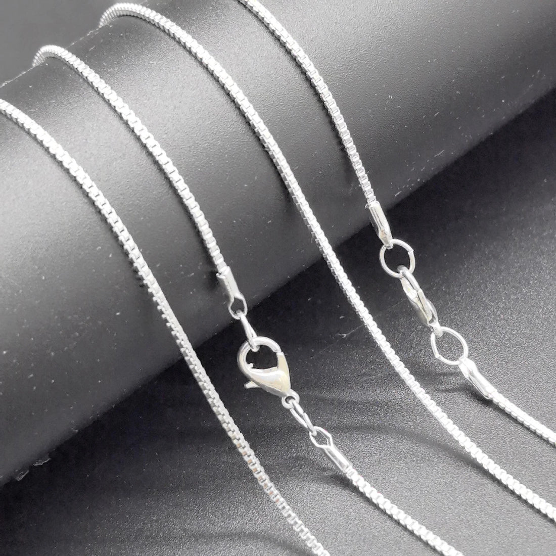 Sleek silver necklace displayed on a dark surface