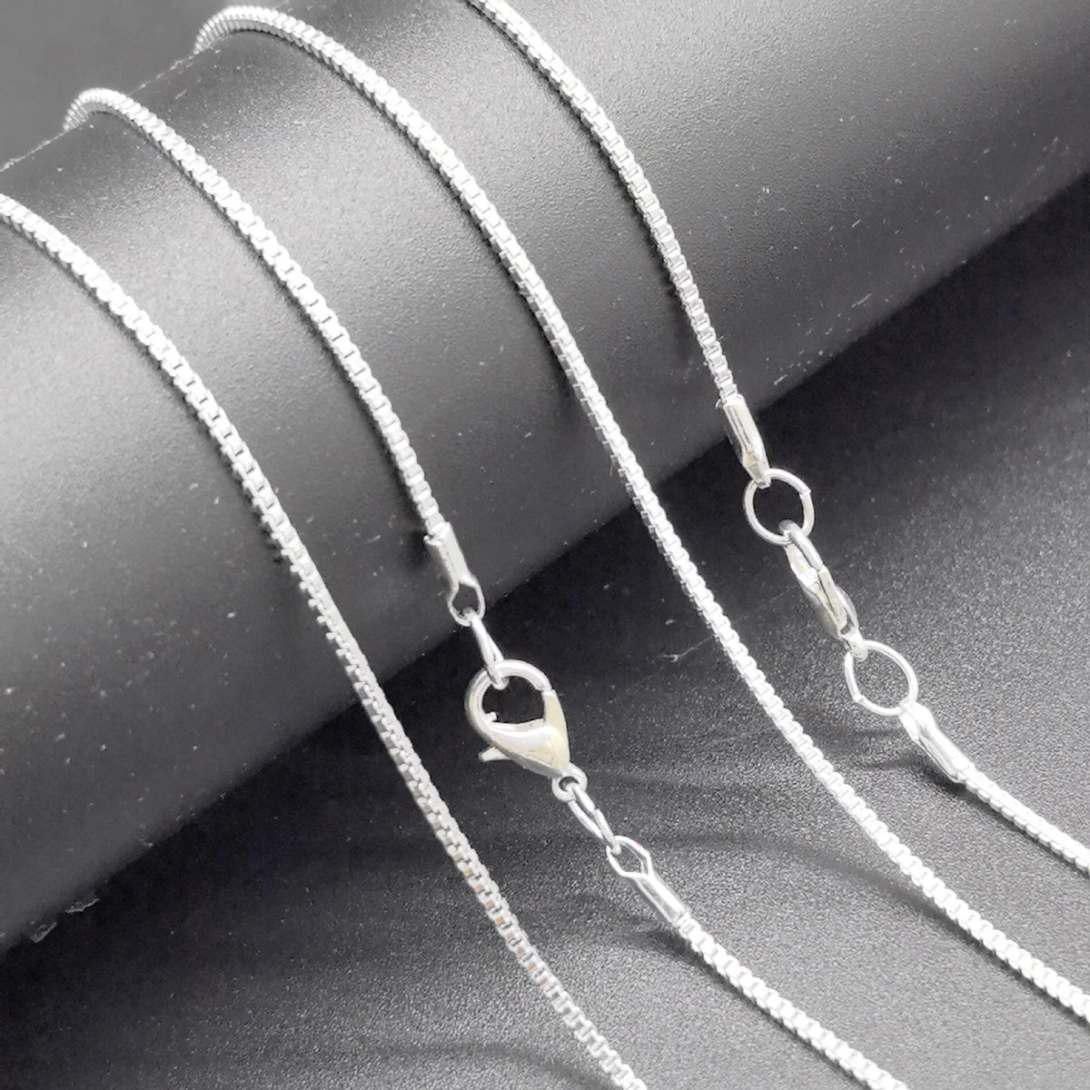 Sleek silver necklace displayed on a dark surface