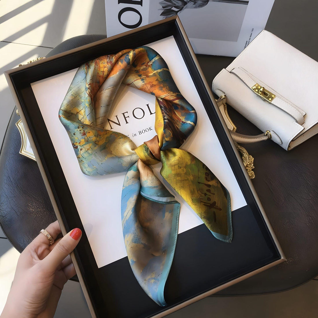 Colorful artistic scarf displayed with a handbag and fashion accessories